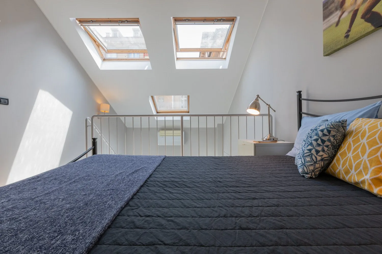 Un dormitorio con una cama bajo un techo inclinado y tragaluces.
