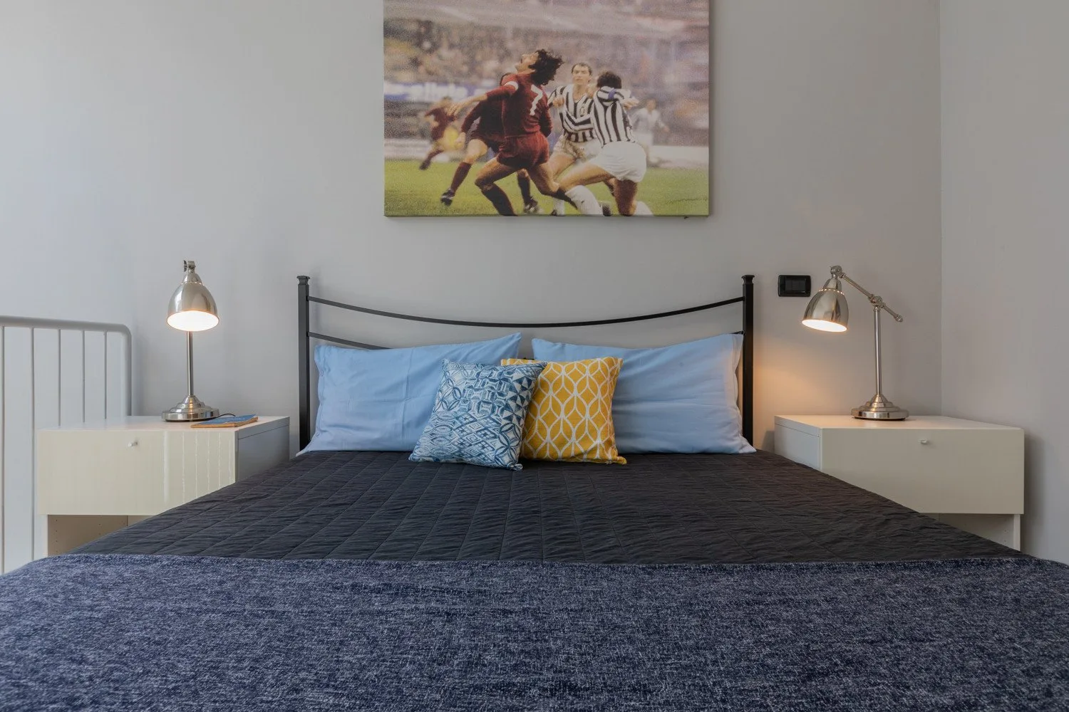 Un dormitorio con una cama bien hecha y una imagen deportiva enmarcada encima.