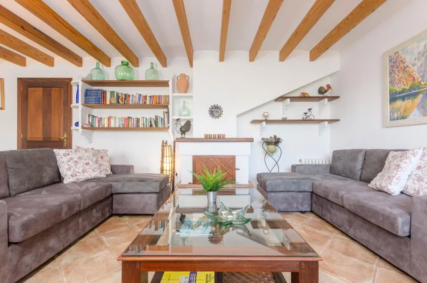 A living room with seating arranged around a glass coffee table and fireplace.