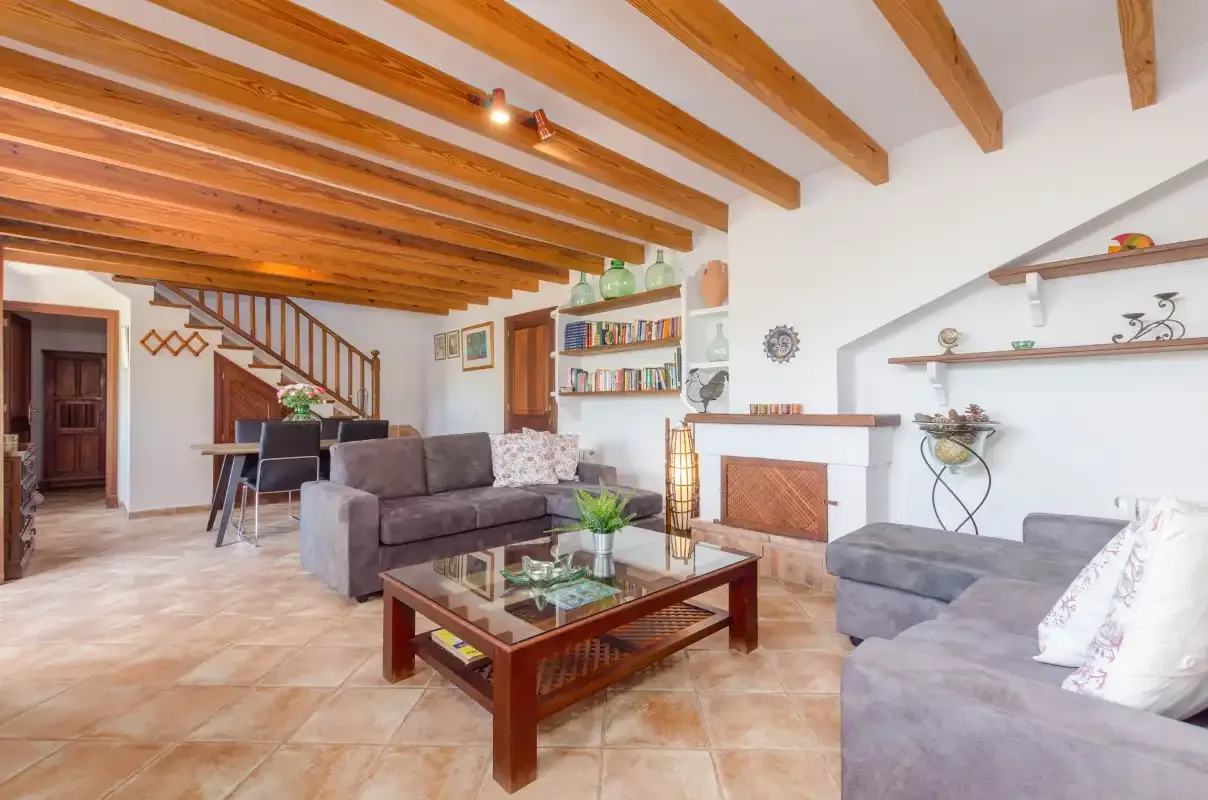 A living room with seating, a fireplace, and exposed wooden ceiling beams.