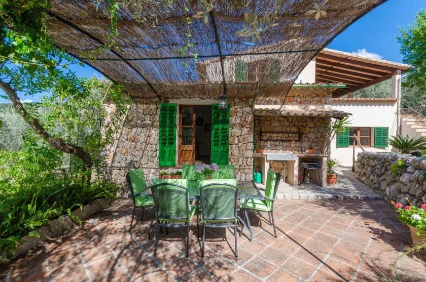 A stone patio with green seating sits beneath a shaded canopy.