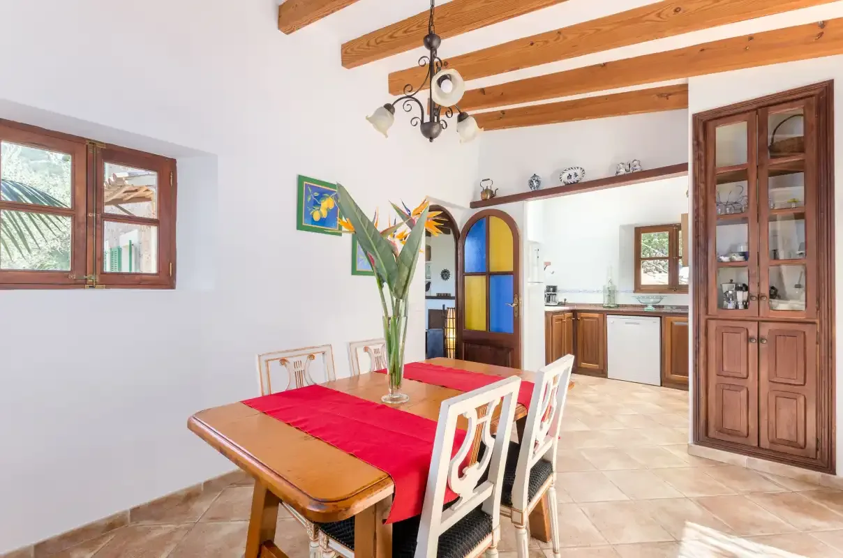A dining area with a wooden table and a kitchen in the background.