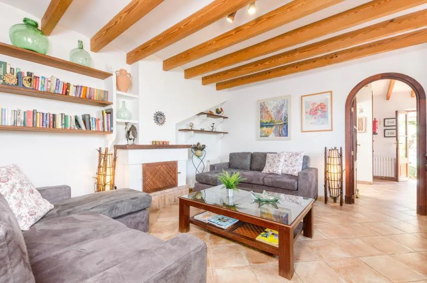 A living room with gray seating, a glass coffee table, and exposed wooden ceiling beams.
