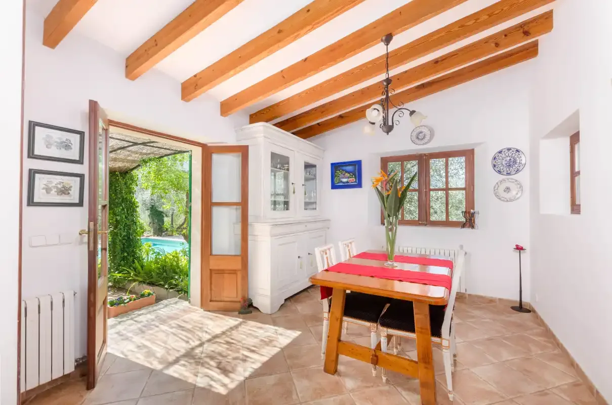 A bright dining area with a wooden table beside an open doorway to the garden.