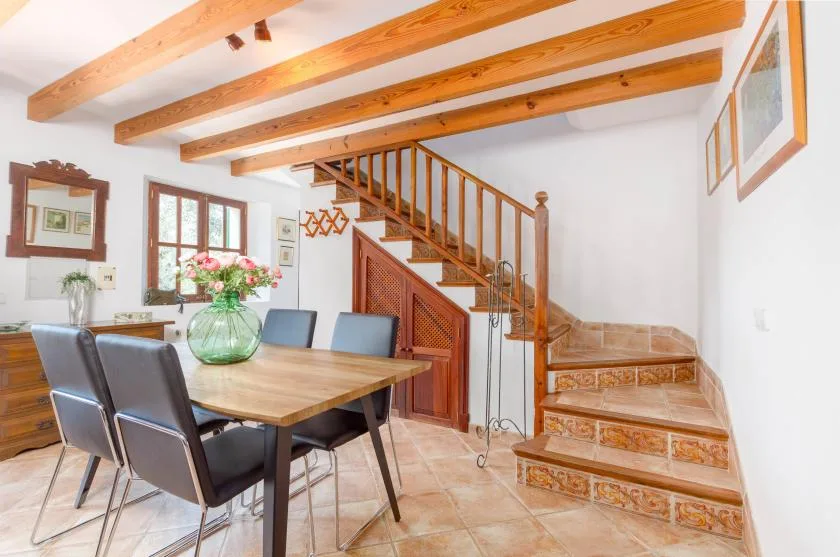 A dining area with a wooden table and chairs beside a staircase.