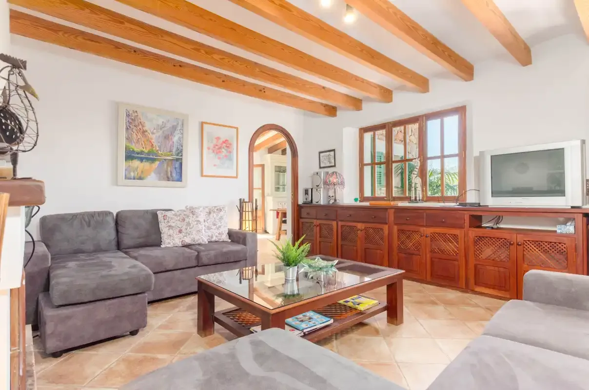 A living room with seating, a wooden coffee table, and exposed ceiling beams.