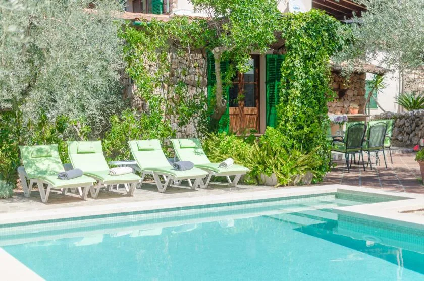 A swimming pool beside lounge seating and a vine-covered building.