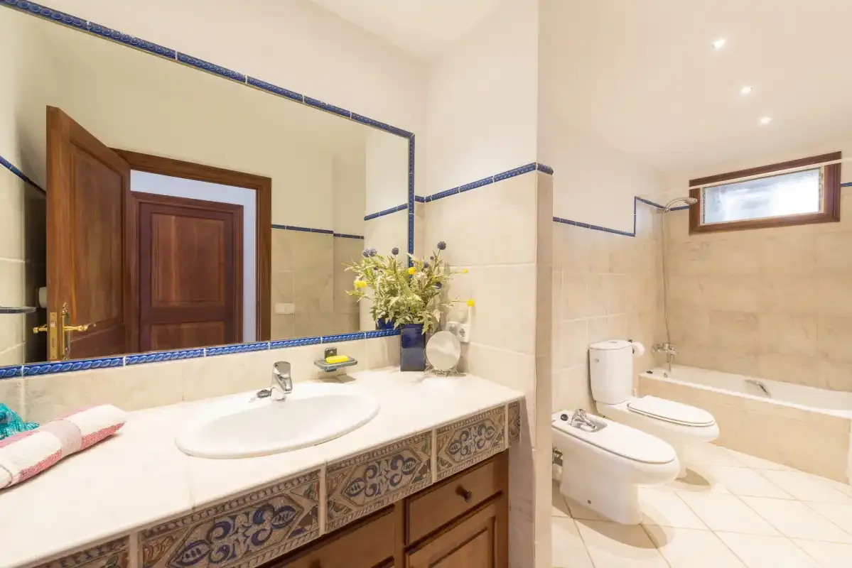 A bright bathroom with a large vanity, mirror, toilet, and bathtub.