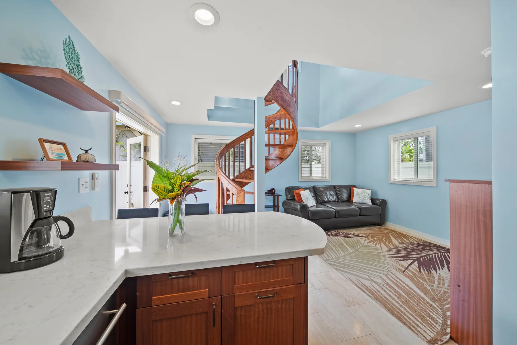 Una cocina y sala de estar diáfanas con una escalera curva y asientos.