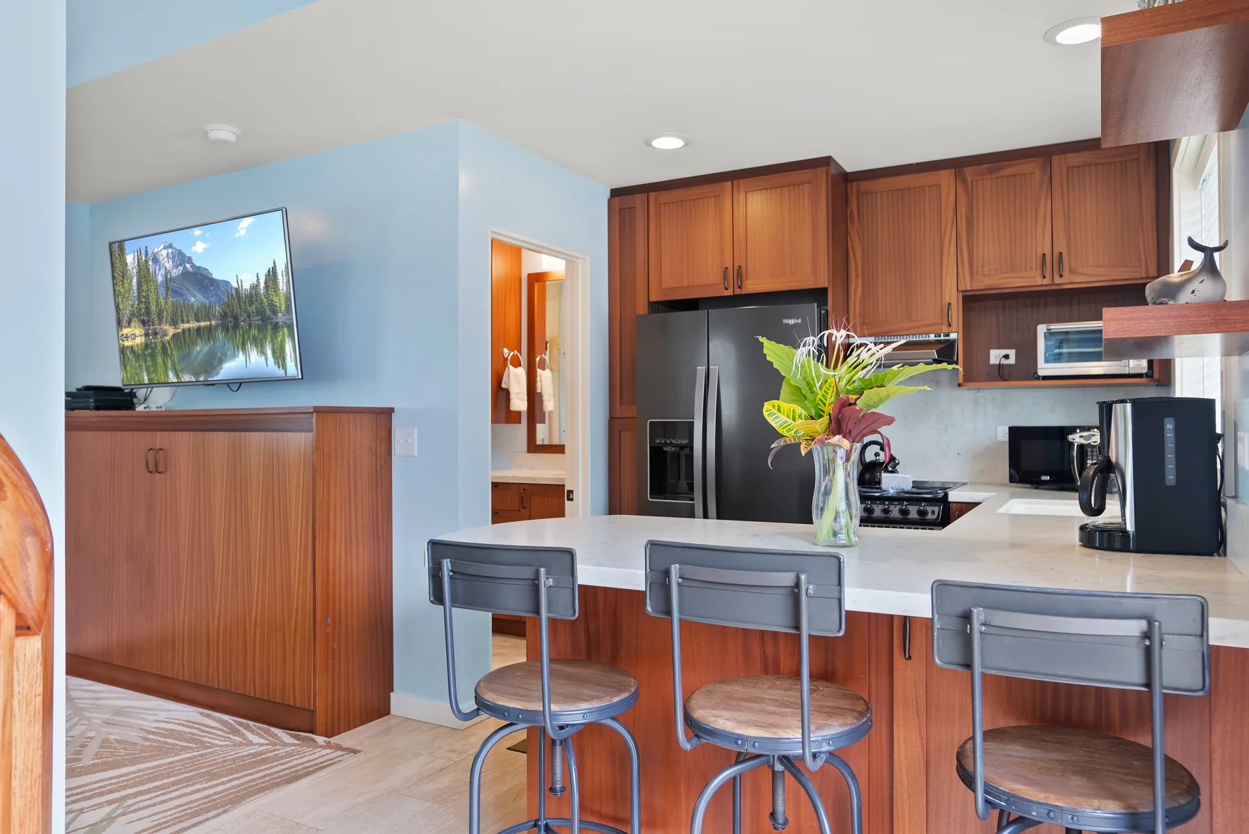 Una cocina luminosa con isla central, asientos de barra y gabinetes de madera.
