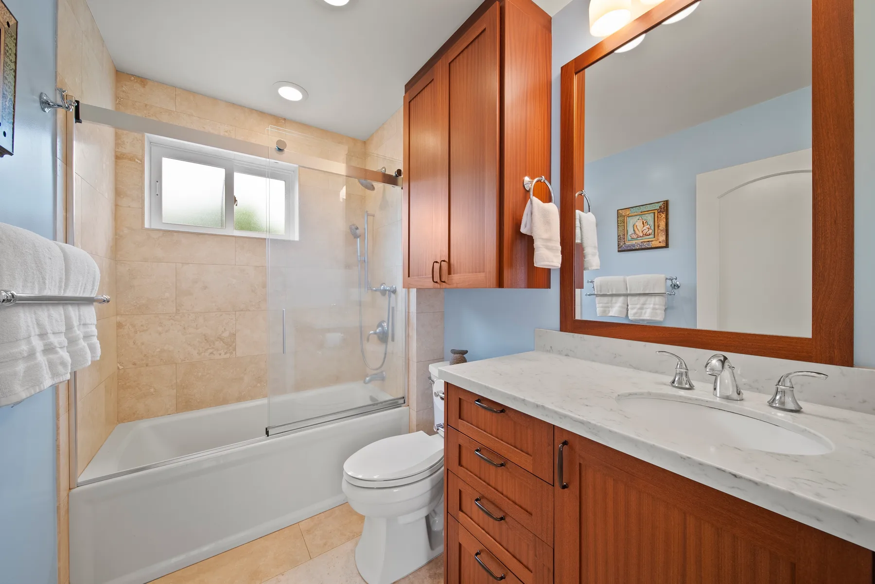 Un baño con bañera y ducha junto a un mueble de lavabo largo.