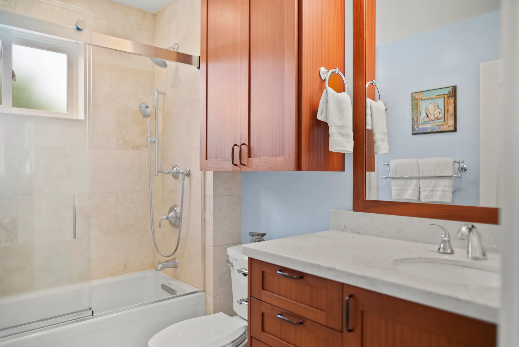 Un baño con ducha de vidrio, tocador y espejo de pared.