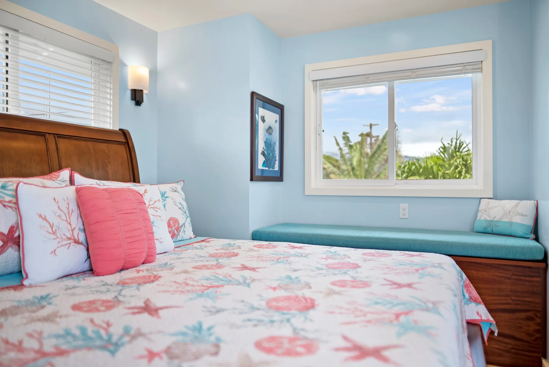 Un dormitorio con una colcha floral y una ventana con vistas a la vegetación.