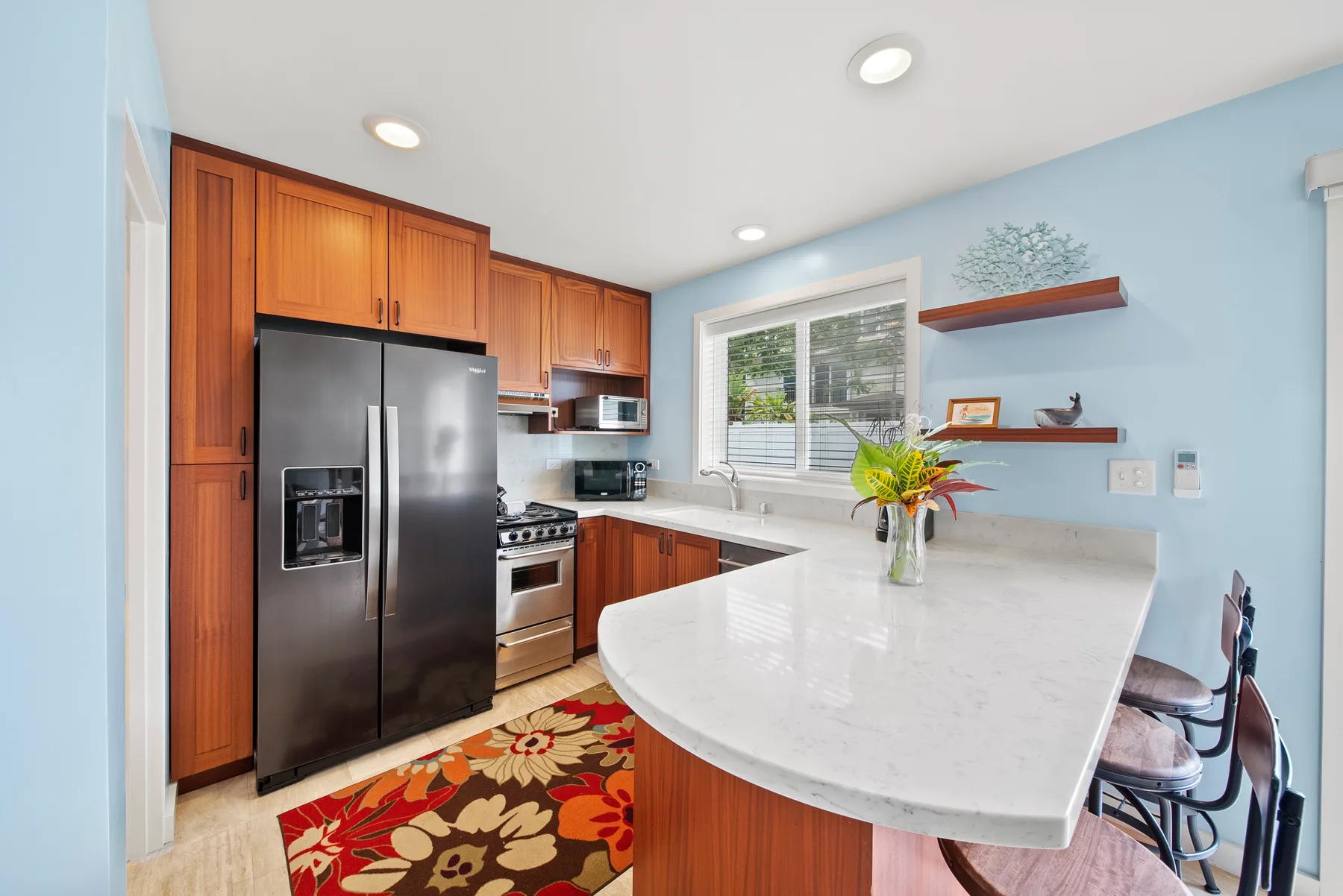 Una cocina luminosa con gabinetes de madera, electrodomésticos de acero inoxidable y una isla curva.