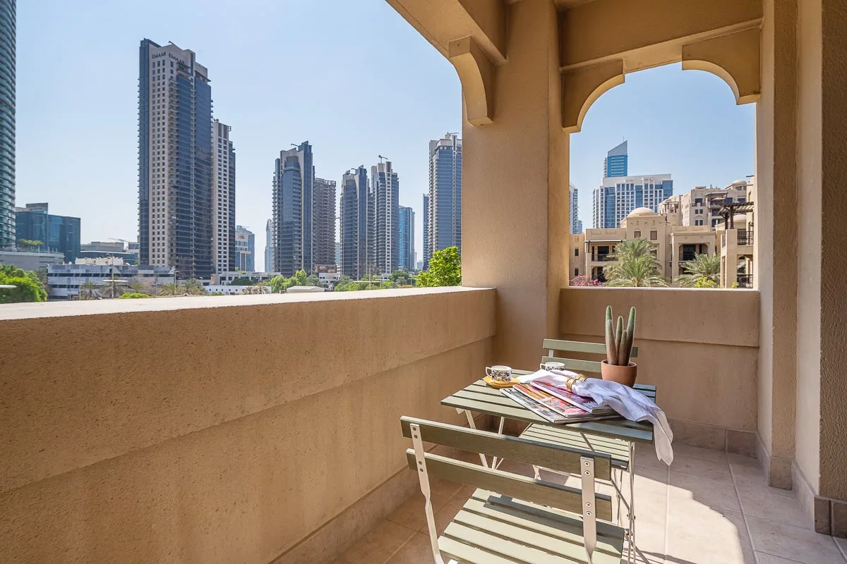 Un balcón soleado con una mesa pequeña y vistas al perfil urbano.