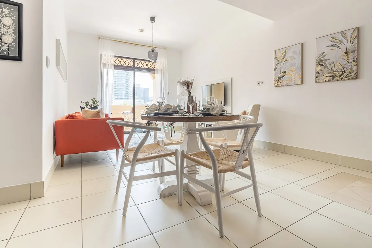 Un comedor luminoso con una mesa de vidrio y asientos junto a una ventana.