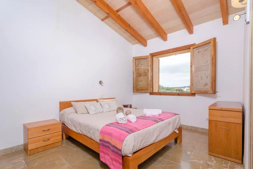 A bedroom with a wooden bed beneath an open window.