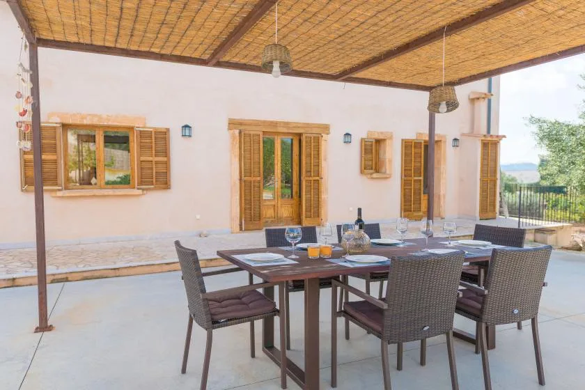 An outdoor dining area with a table and seating beneath a covered patio.