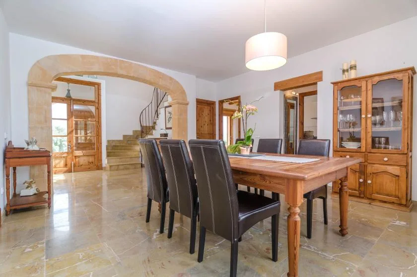 A dining room with a wooden table and chairs beneath a stone archway.
