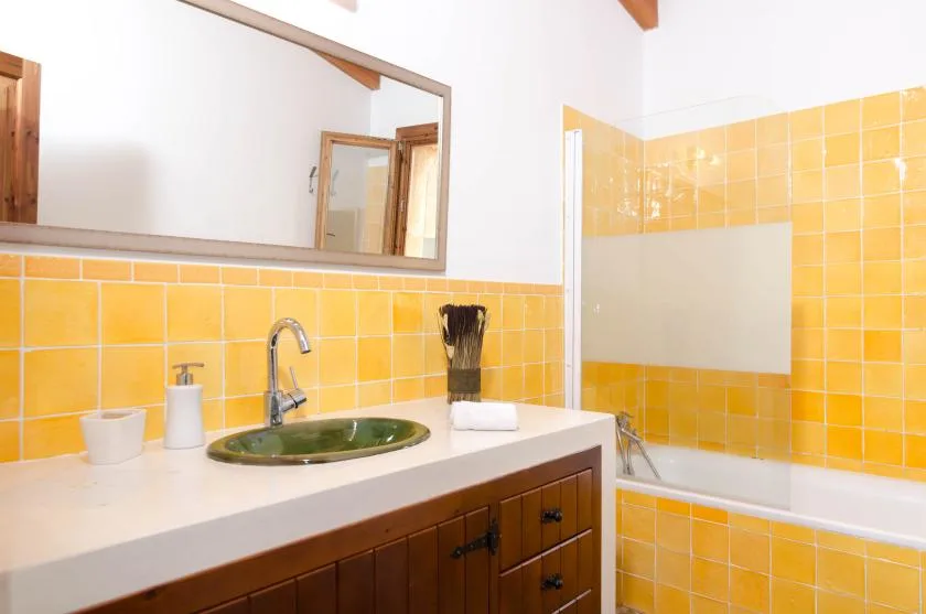 A bathroom vanity with a green sink sits beside a bathtub.