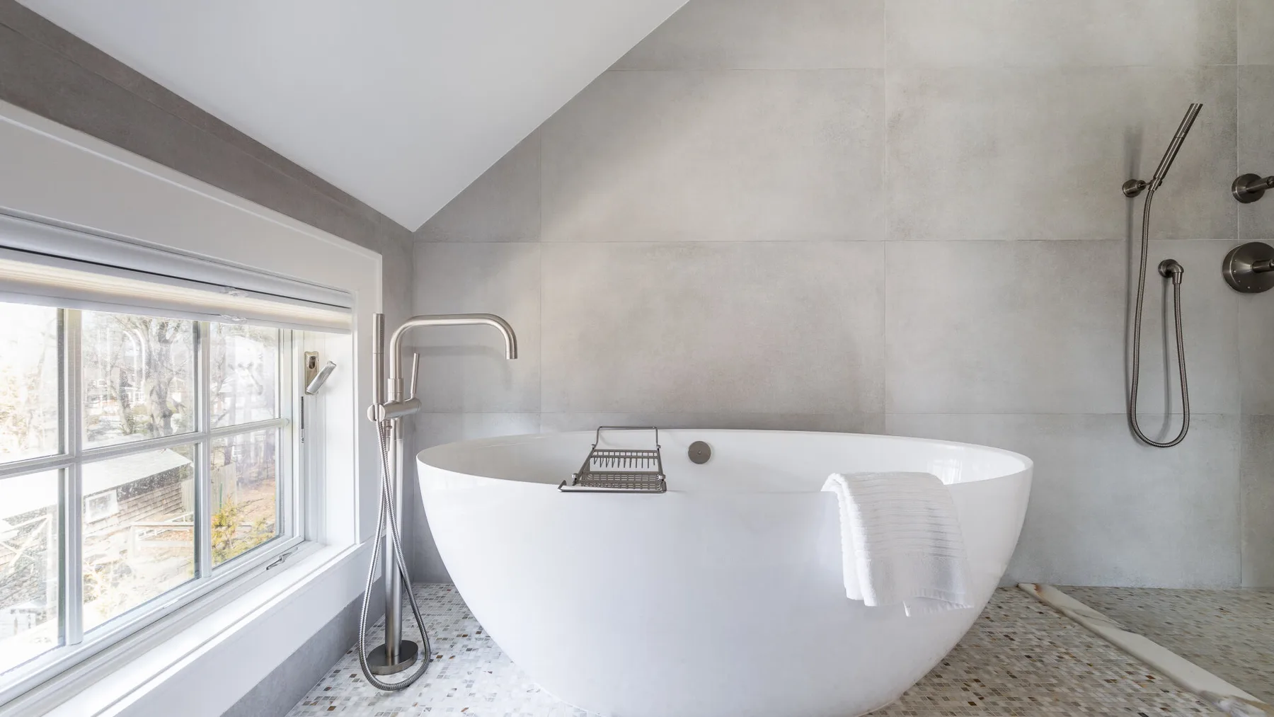 A bathroom with a freestanding bathtub beside a large window.
