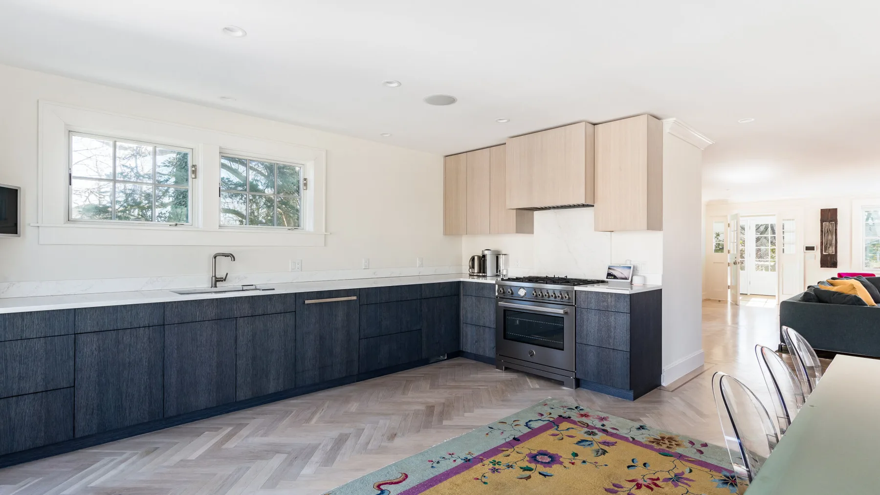 A bright open-plan kitchen with dark lower cabinets and a dining area.