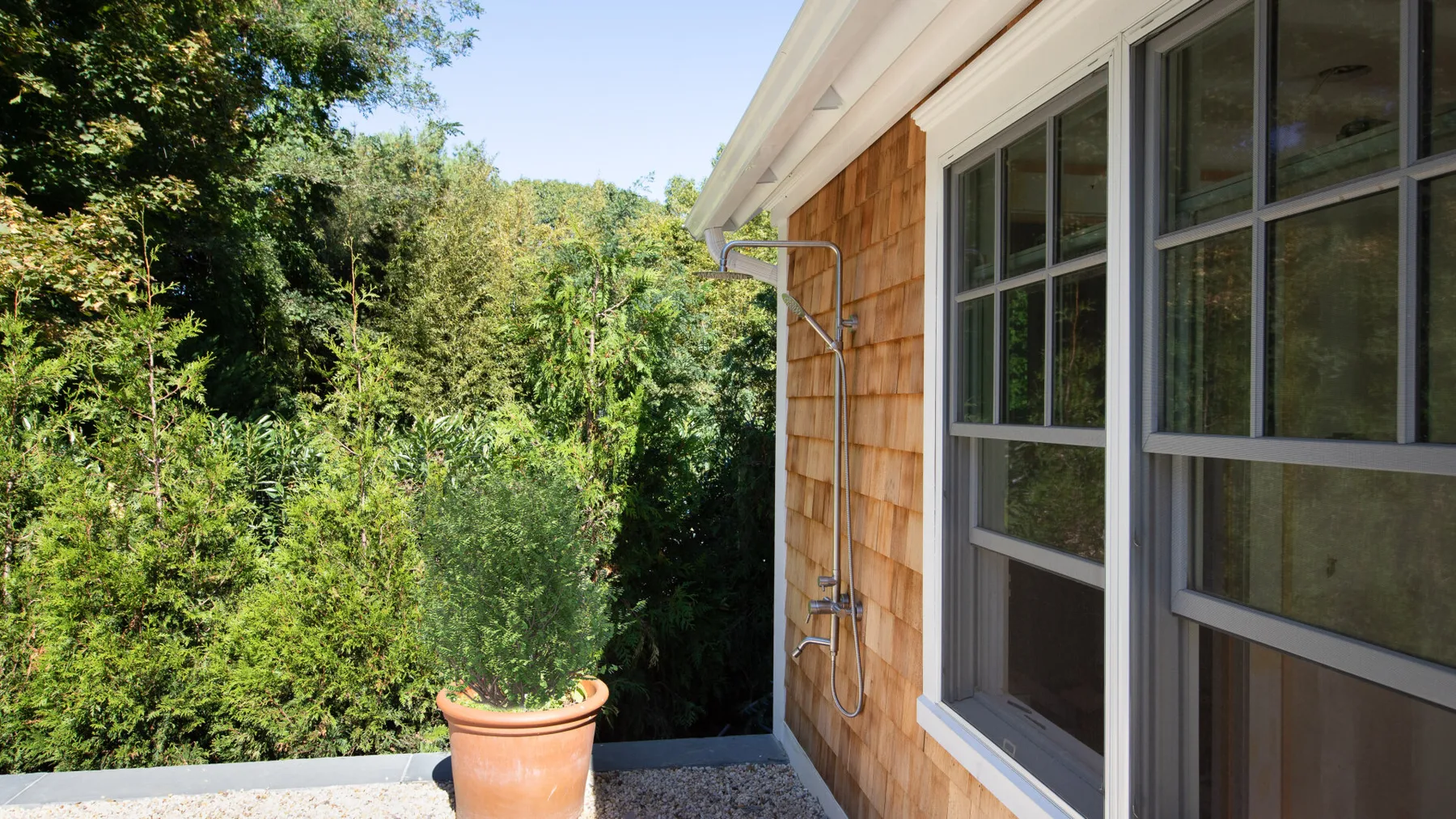 An exterior walkway borders a wood-sided building and dense greenery.