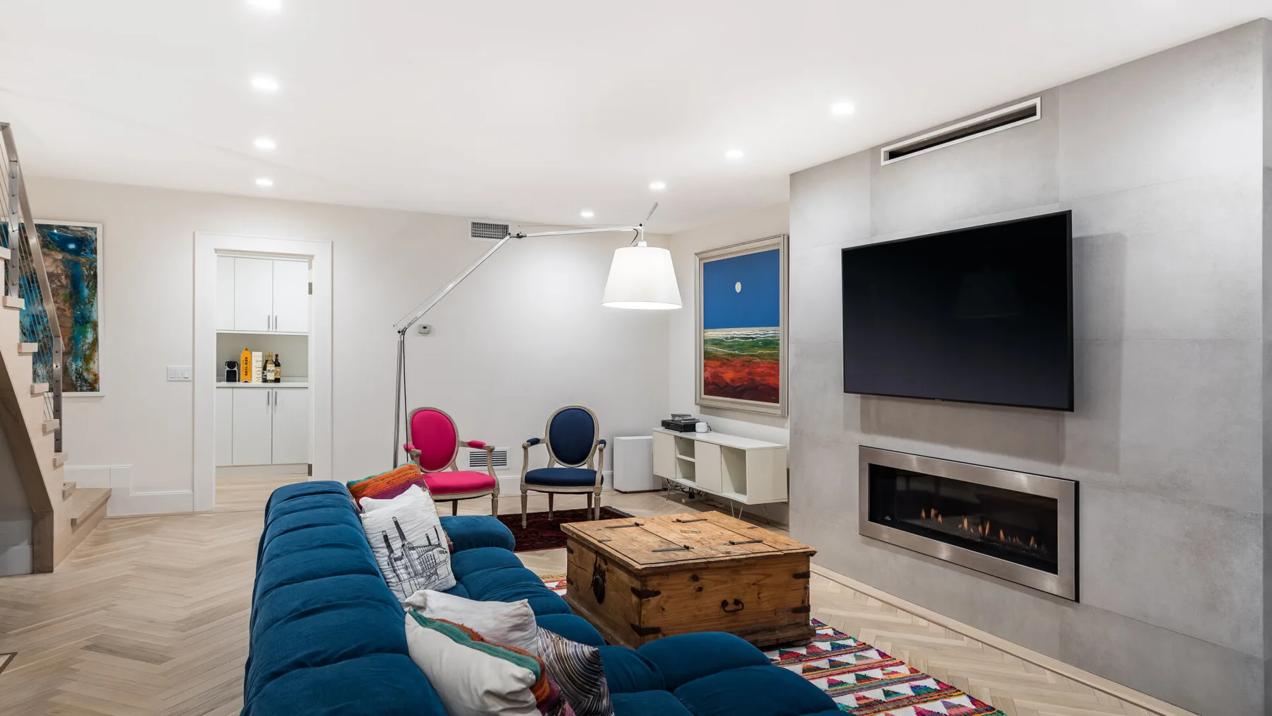 A bright living room with blue seating, a coffee table, and a wall-mounted television.