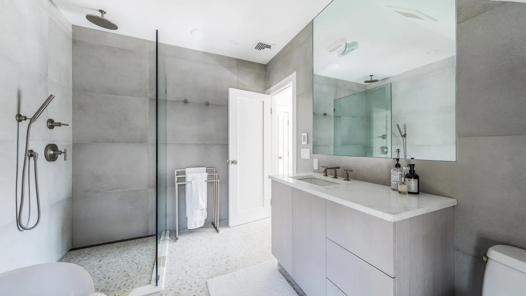 A bright bathroom with a glass shower and a wide vanity.