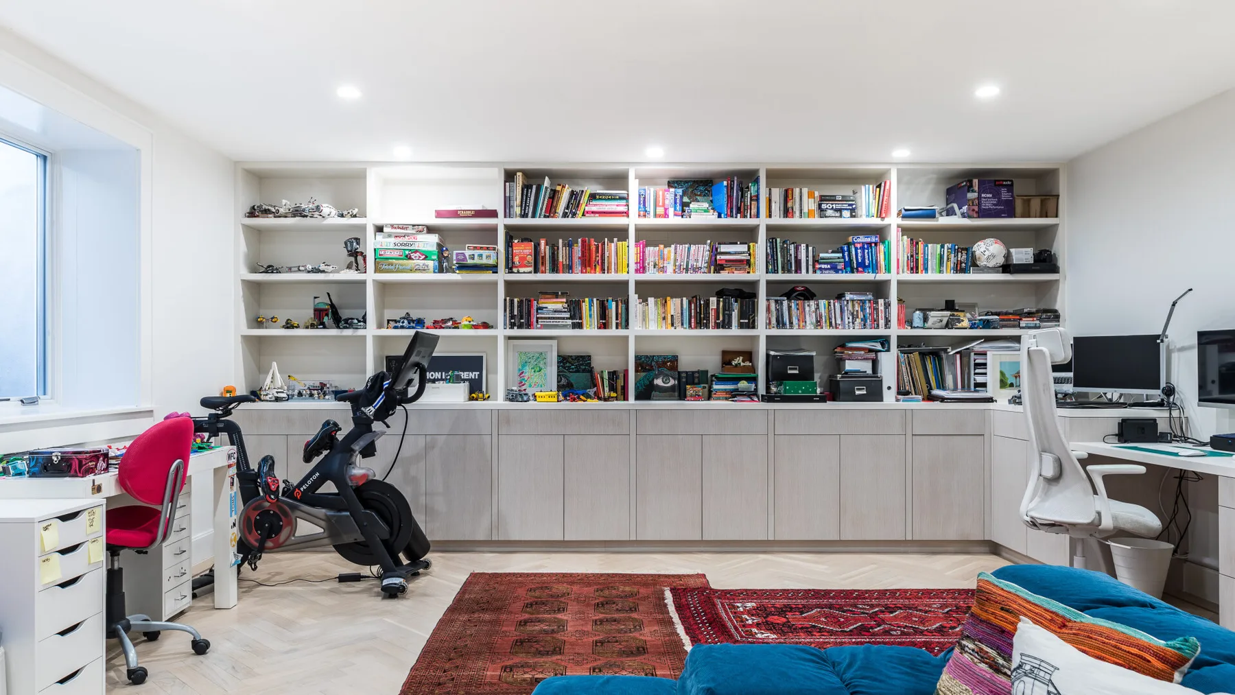 A home office and exercise area with bookshelves, desks, and exercise equipment.