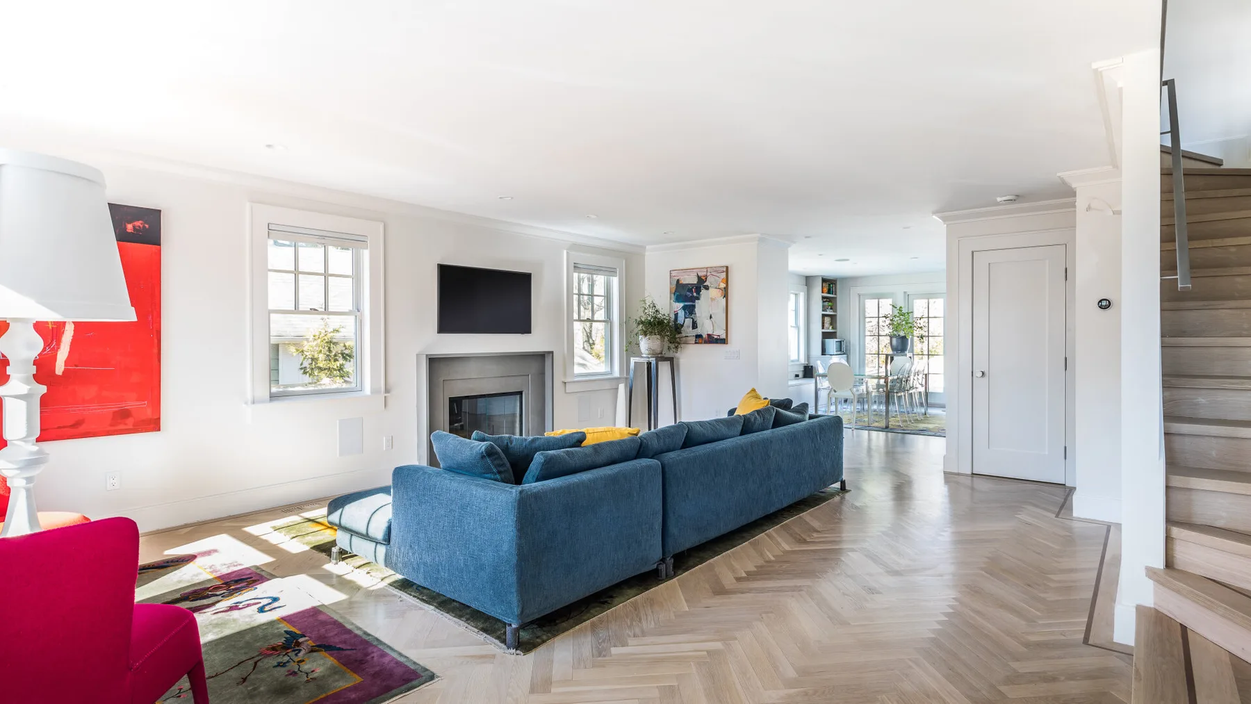 A bright living room with blue seating and a television above the fireplace.