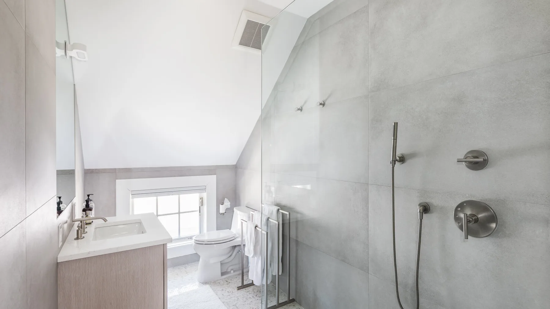 A bright bathroom with a vanity, toilet, and shower.