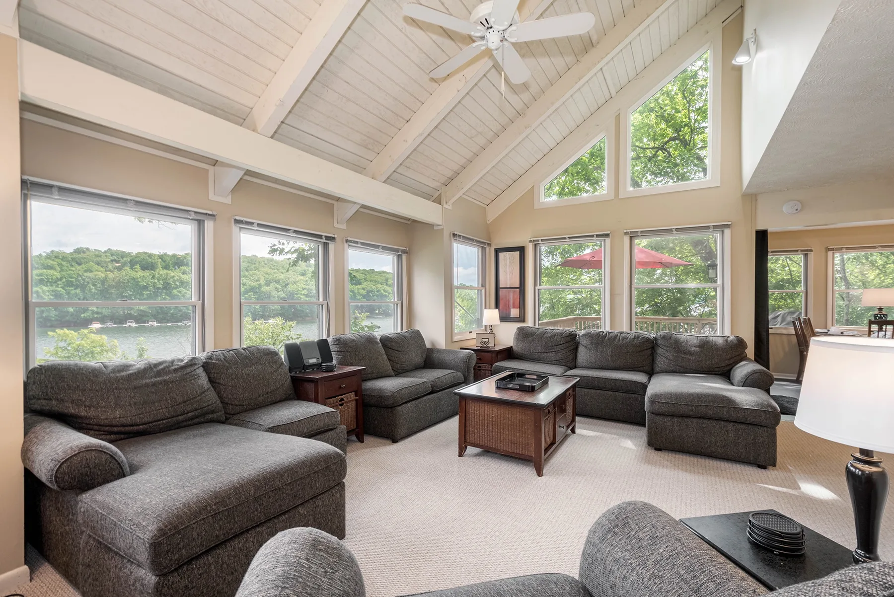 A spacious living room with gray sectional seating, large windows, and a vaulted ceiling.