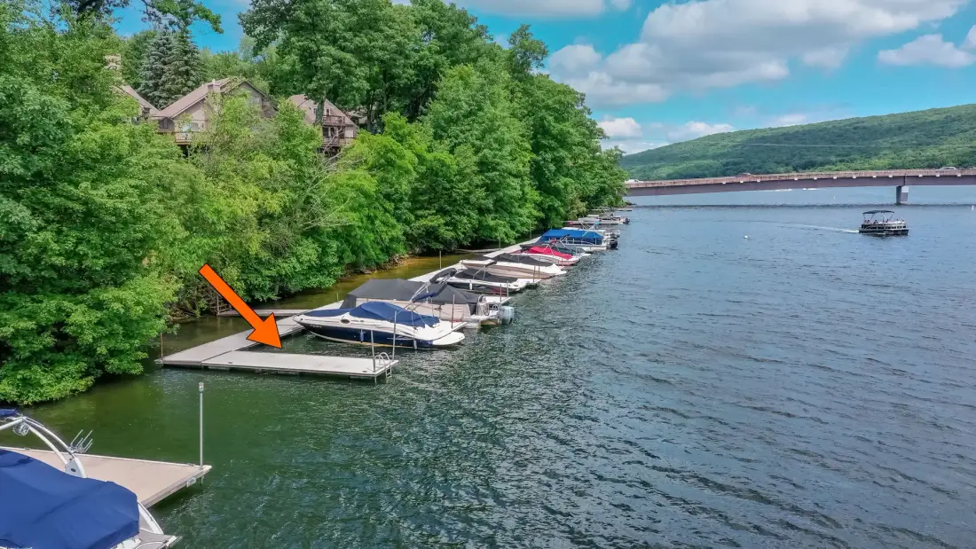 A lakeside marina with boats docked along a wooded shore.