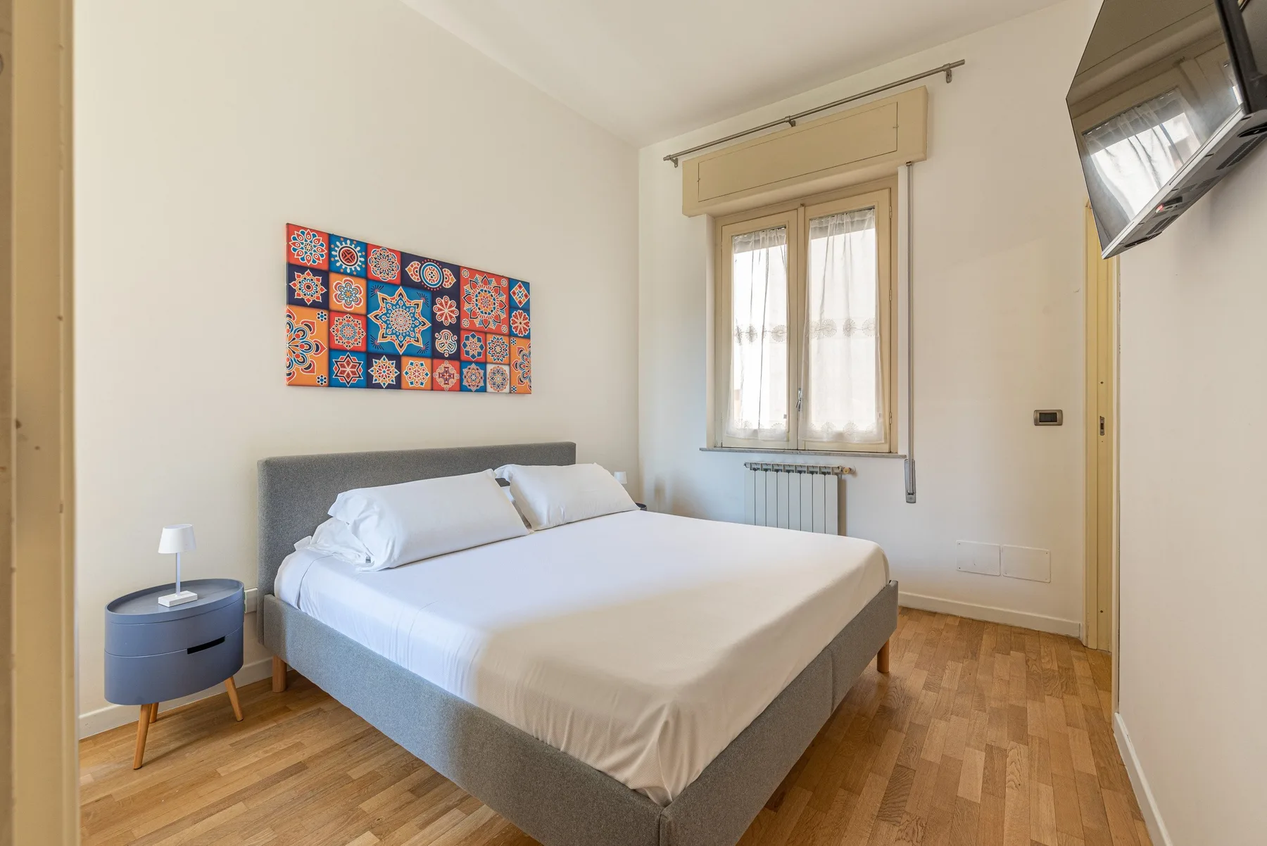 Dormitorio con una cama bien hecha bajo una ventana.