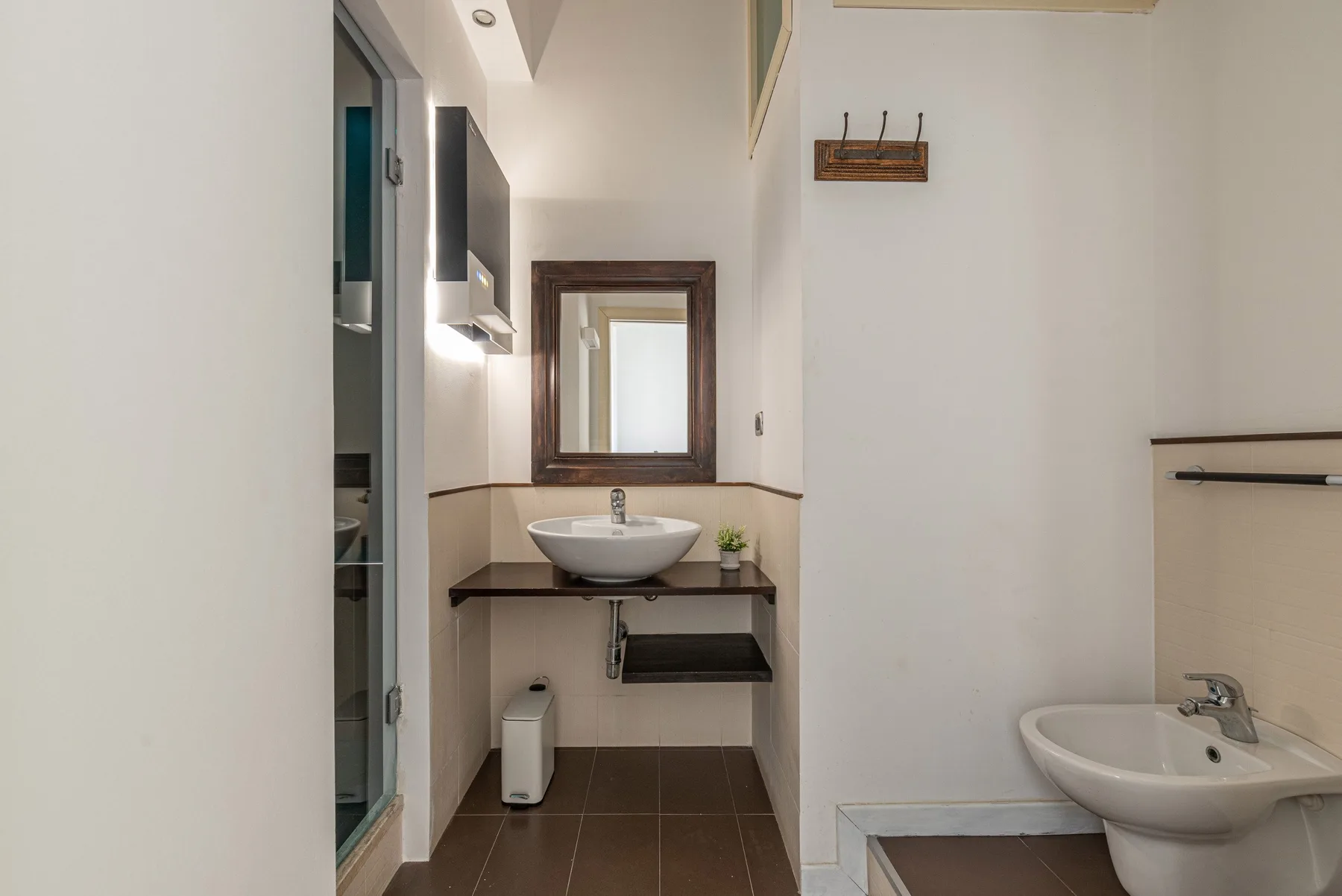 Un baño con lavabo, espejo y otro lavabo en primer plano.