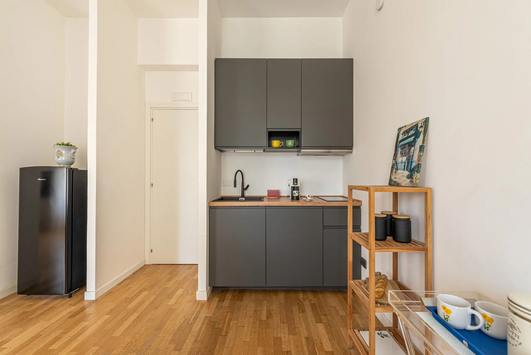 A compact kitchen with dark cabinets, a sink, and a small refrigerator.