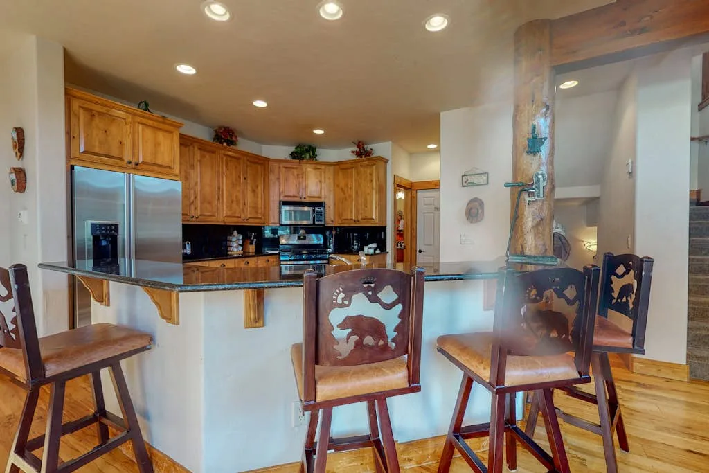A kitchen with wooden cabinets and a counter with bar seating.