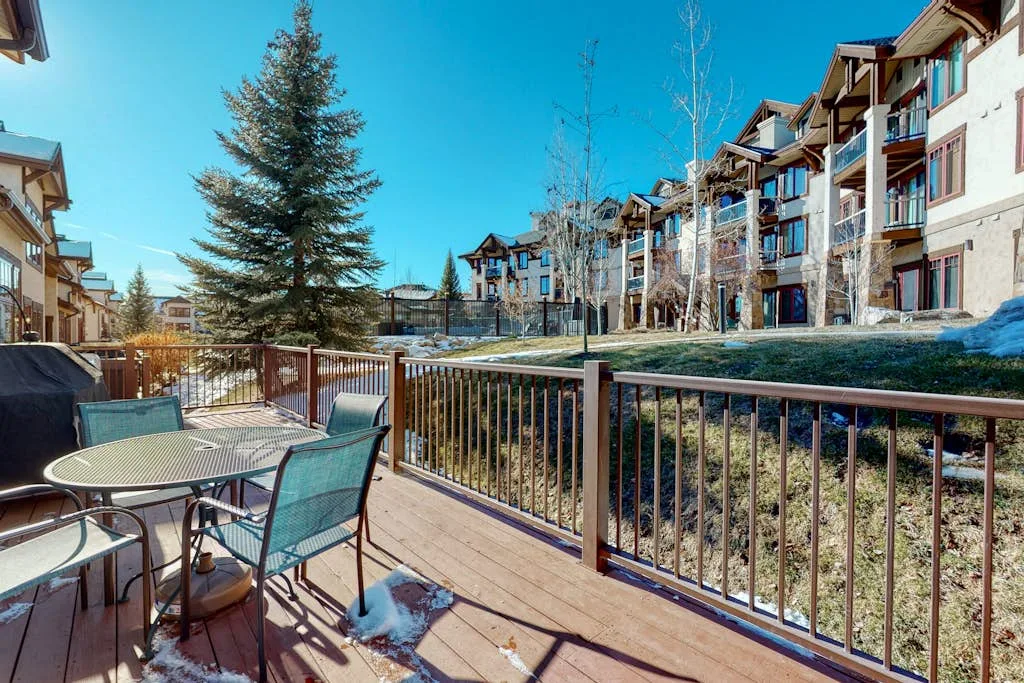 A patio seating area overlooks a row of multi-story buildings and a landscaped slope.