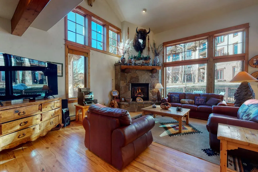 A spacious living room with leather seating, a fireplace, and large windows.