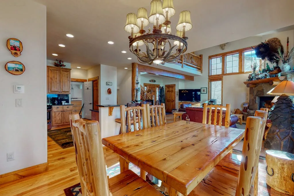 A dining area with a long wooden table and an open kitchen beyond.