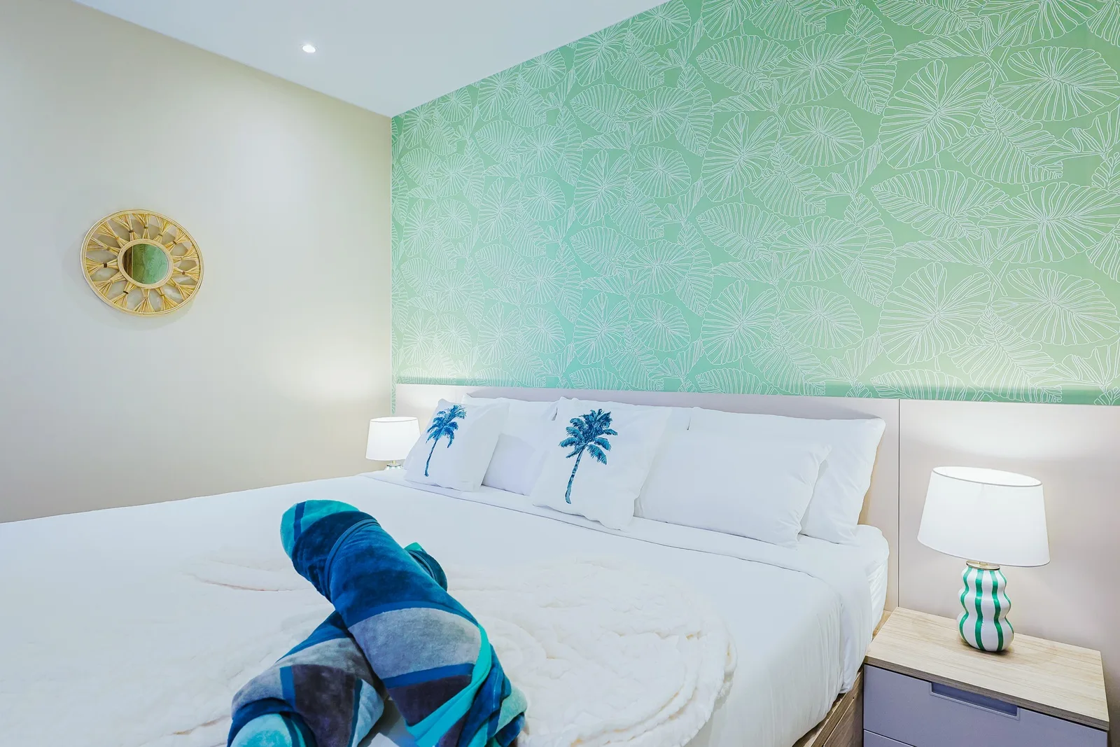Sink into crisp white linens and let the tropical palm-print accent wall transport you to your island getaway. Soft bedside lamps and cheerful decor set the tone for your restful retreat.