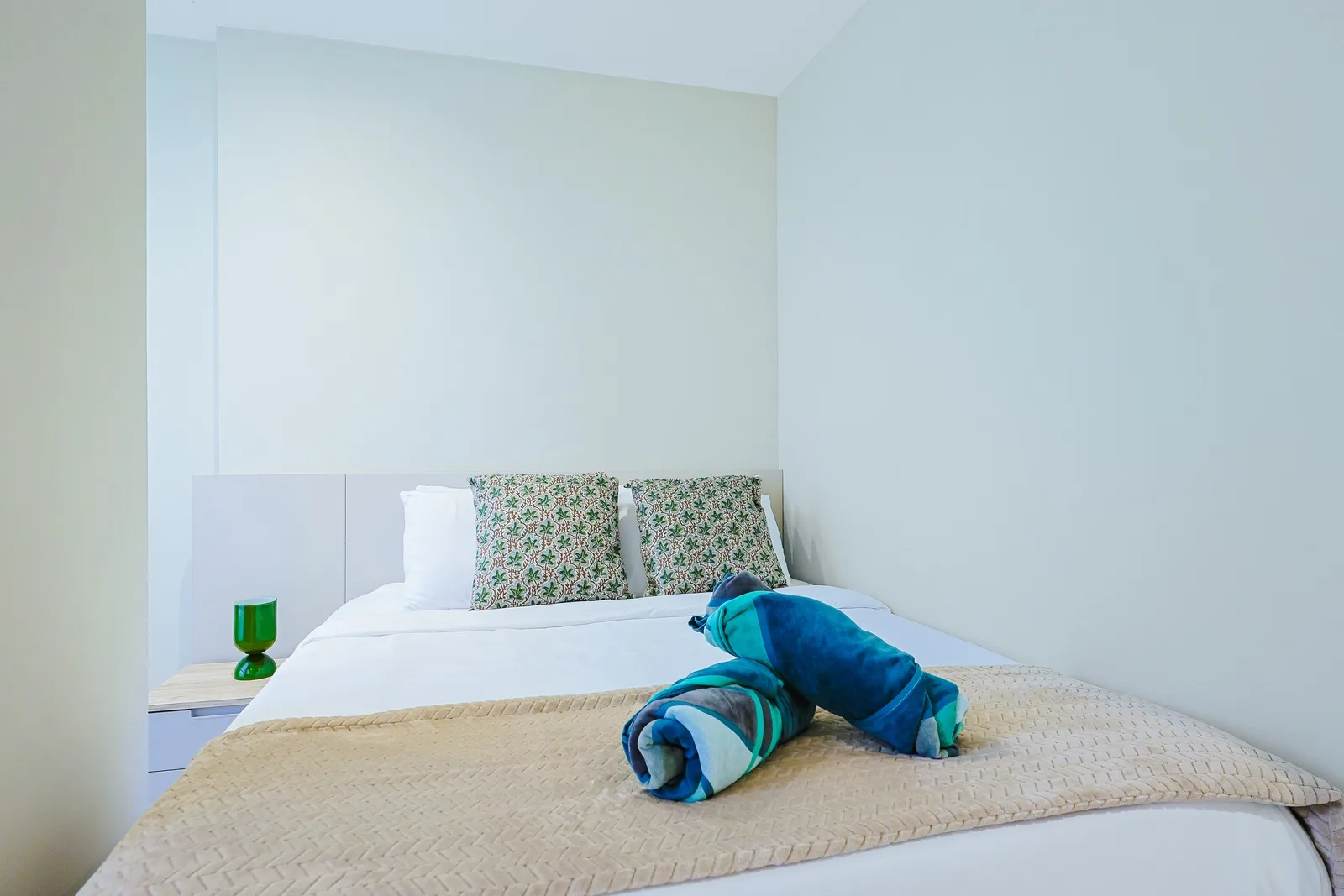 Sink into crisp linens and floral-print pillows in your bright, minimalist bedroom. The simple white décor creates a calming atmosphere for restful nights.