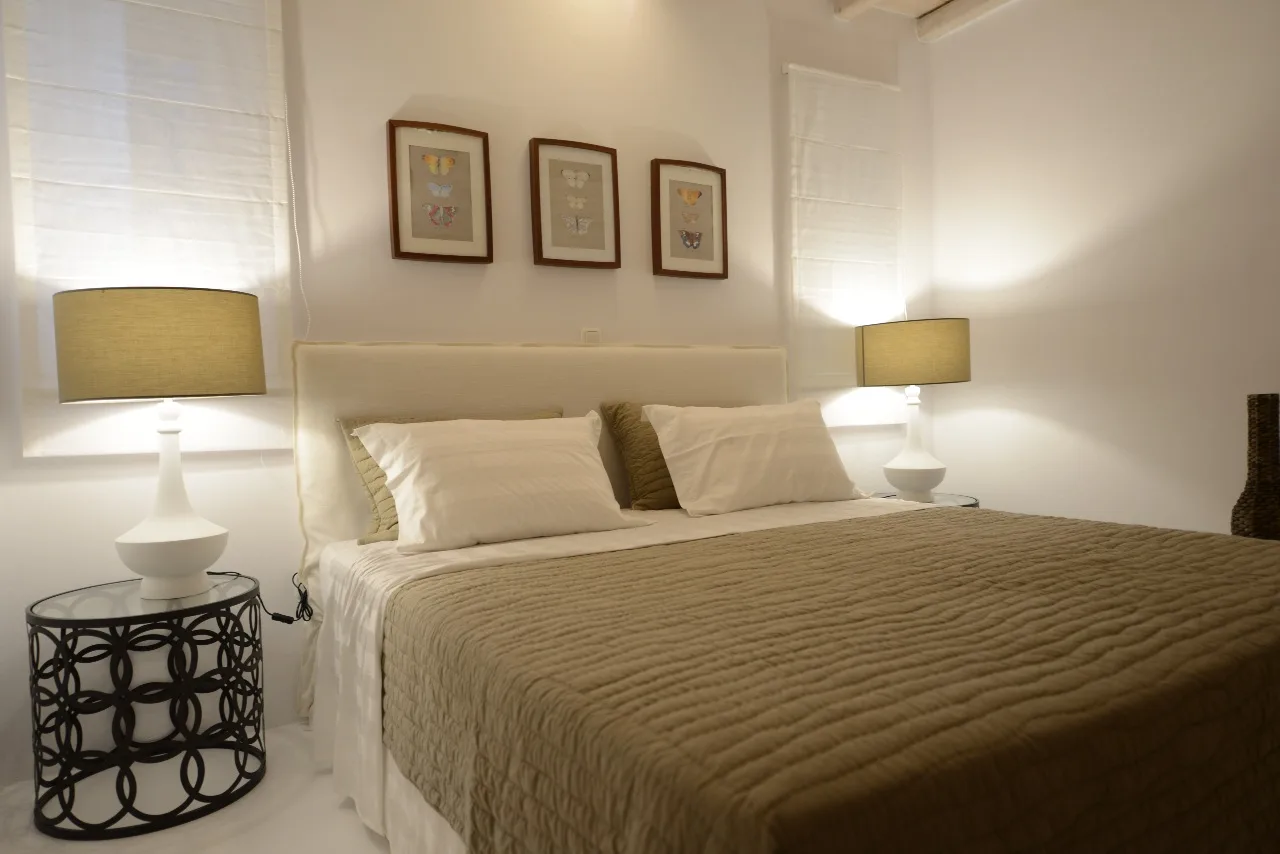 Un dormitorio con una cama bien tendida y lámparas a ambos lados.