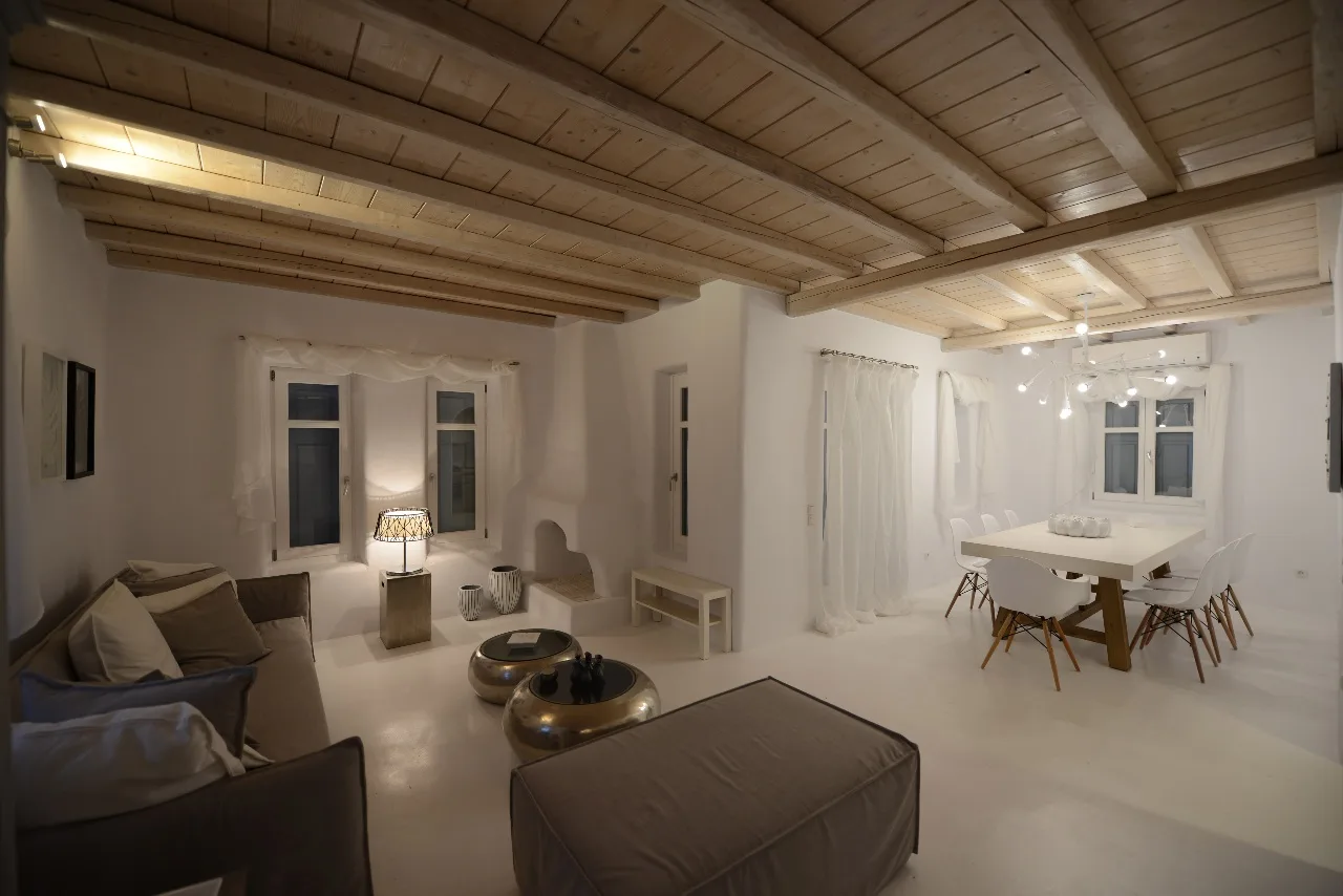 Una sala de estar y comedor con asientos, una mesa y vigas de madera expuestas en el techo.