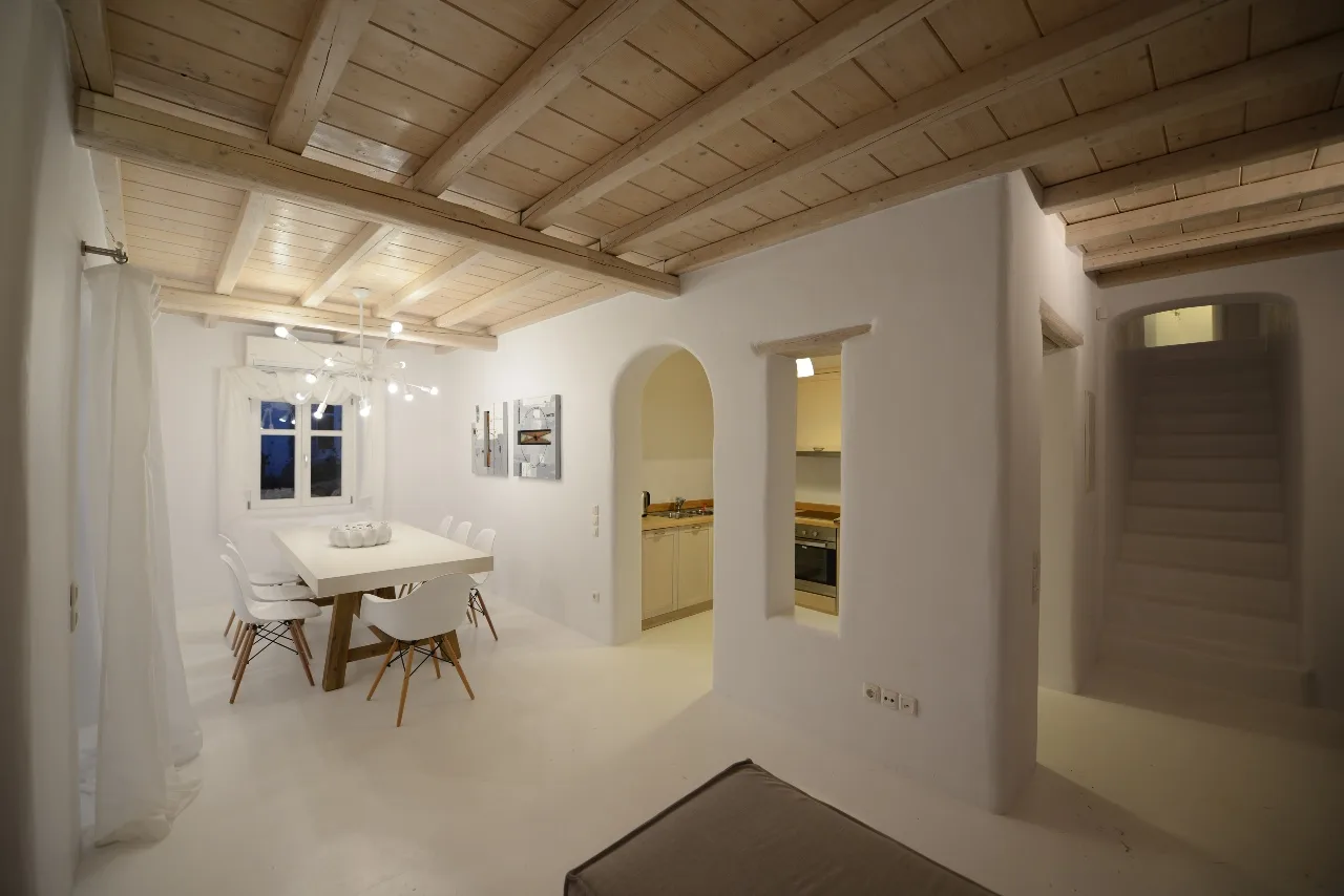 Un comedor luminoso con una mesa bajo vigas de madera vistas.