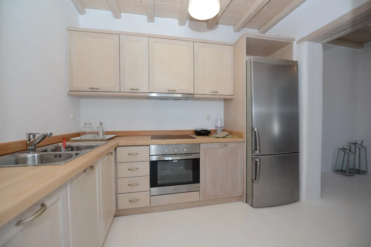 Una cocina con gabinetes de madera clara, fregadero y electrodomésticos empotrados.