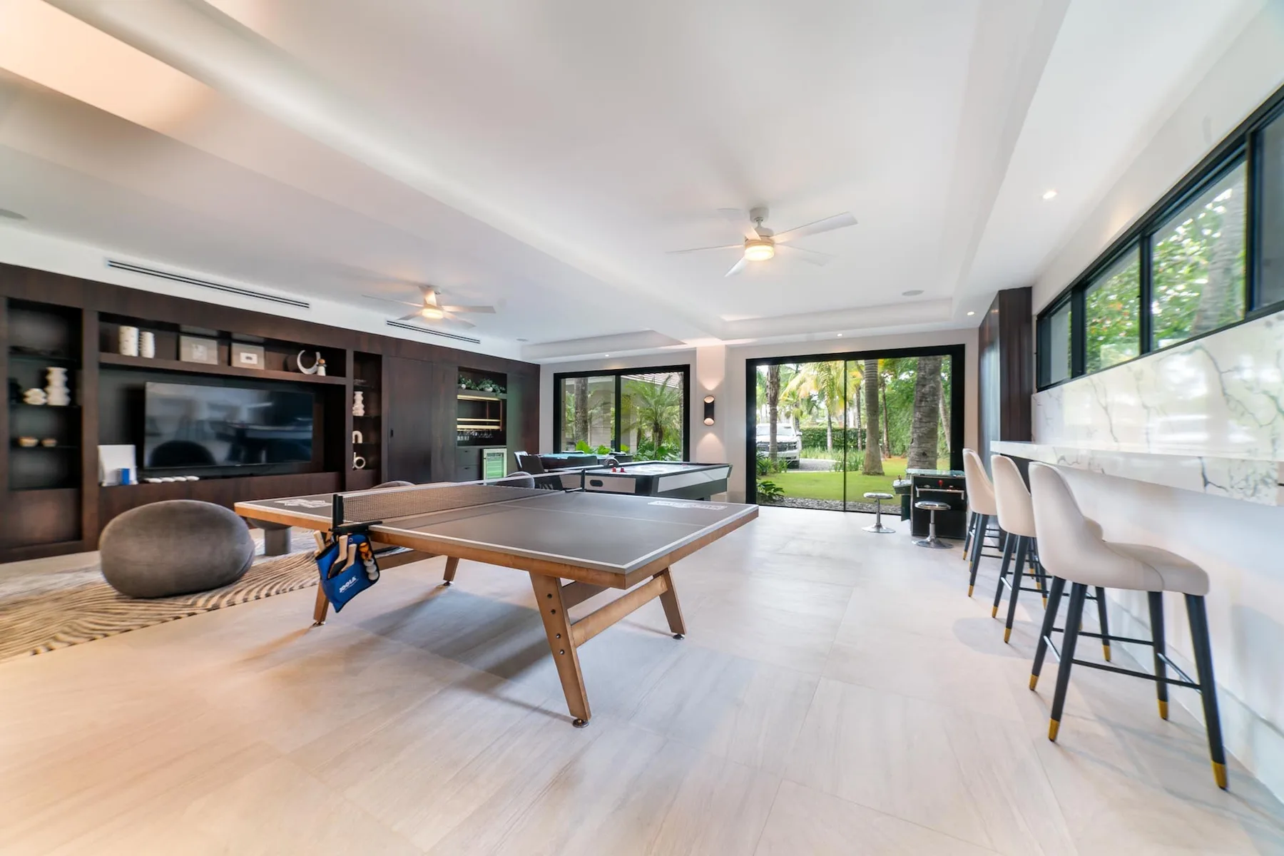 A bright recreation room with a ping-pong table, television, and seating.