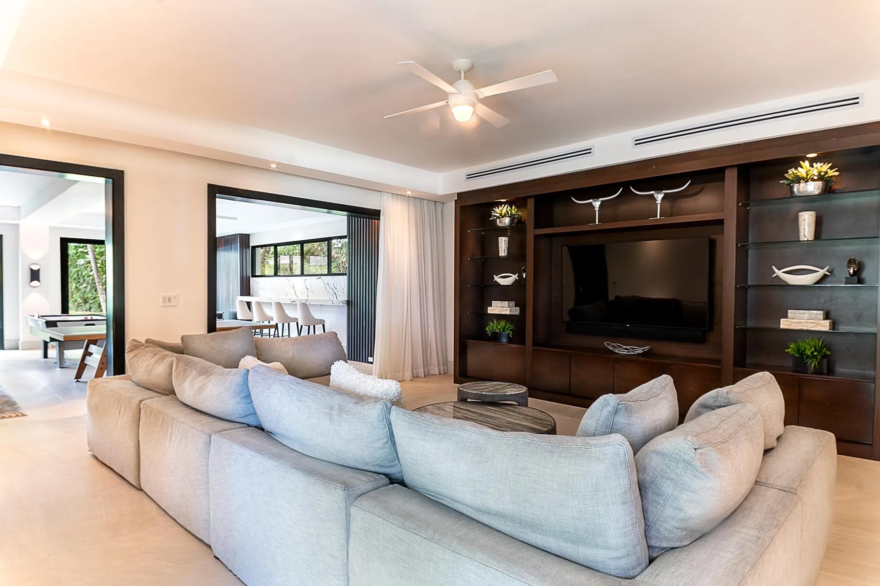 A living room with pale seating arranged around a television.