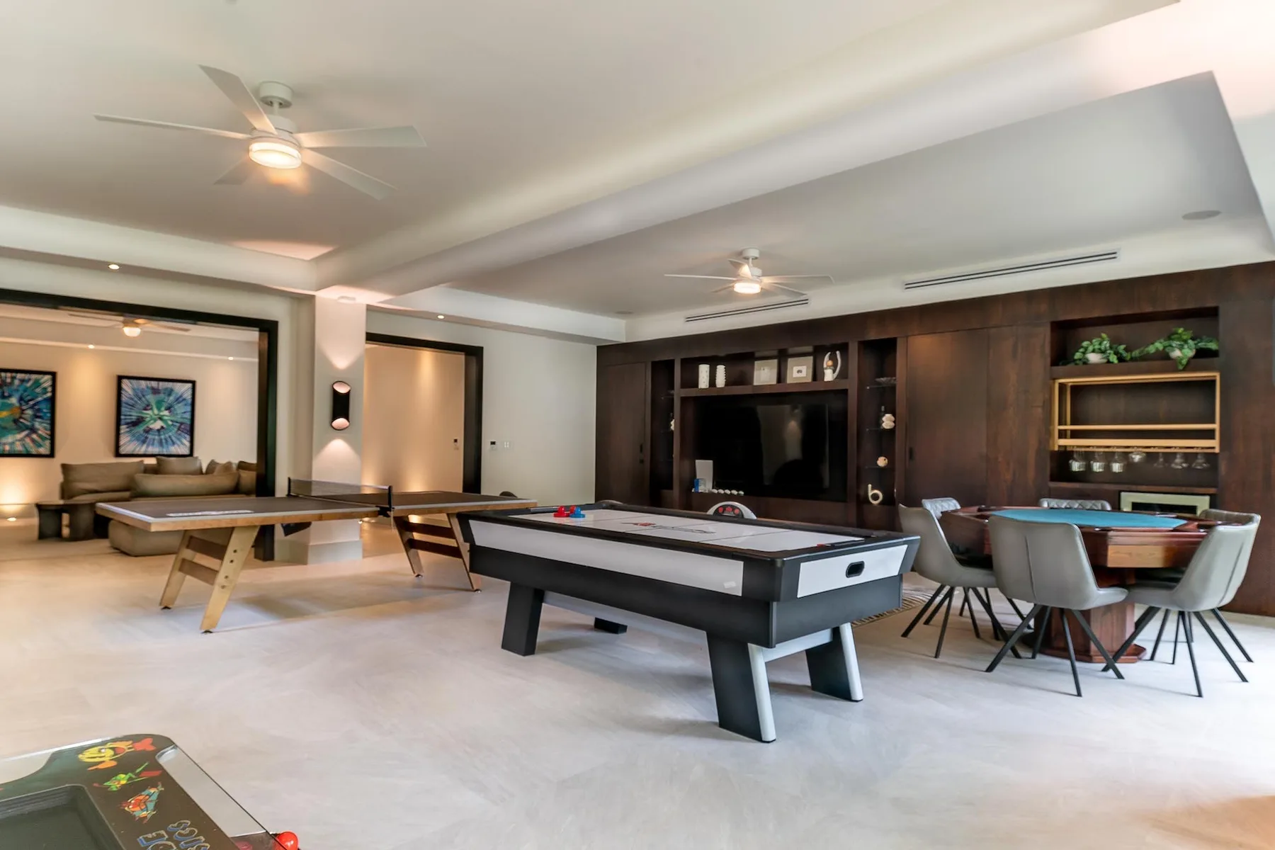 A recreation room features a pool table, a ping-pong table, and seating.